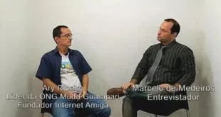 Dois homens sentados frente a frente em entrevista gravada, com legendas sobre a imagem