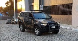 Viatura policial preta estacionada em frente a prédio institucional