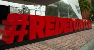 Letreiro tridimensional vermelho com hashtag em letras grandes na entrada de um prédio