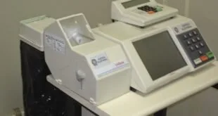 Urnas eletrônicas de votação sobre mesa em sala de ambiente interno