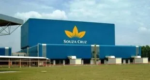Fachada azul de fábrica com o logotipo da Souza Cruz acima das docas de carga
