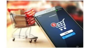 Celular com tela de carrinho de compras diante de carrinho de supermercado em miniatura
