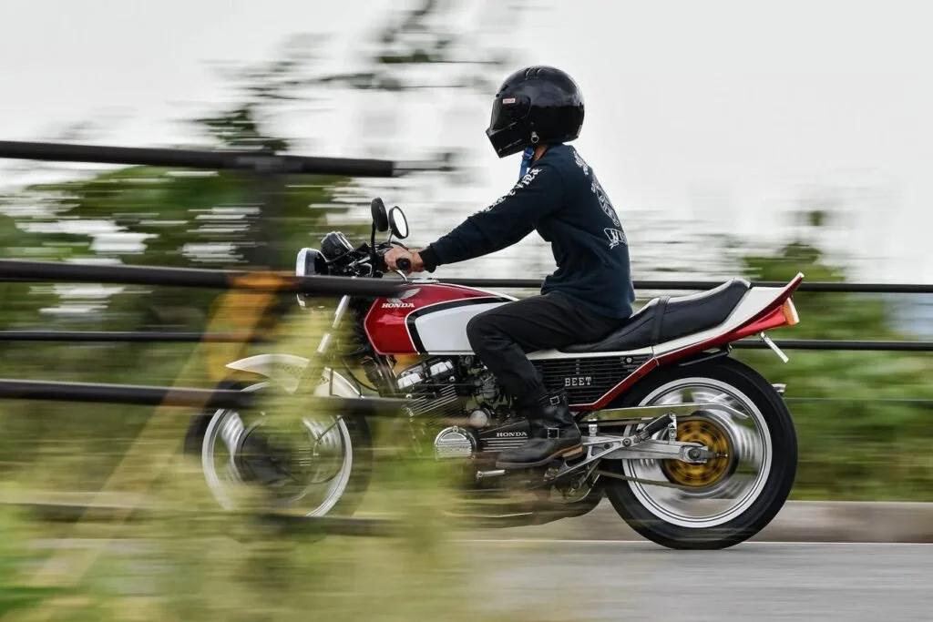 Motociclista de capacete pilota moto vermelha em movimento, com o fundo desfocado