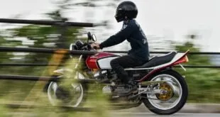 Motociclista de capacete pilota moto vermelha em movimento, com o fundo desfocado