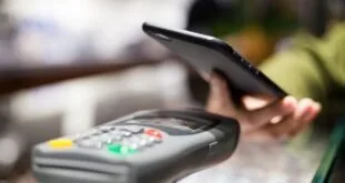Mão com celular sobre máquina de cartão para pagamento por aproximação