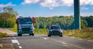 Caminhão e carro trafegando em rodovia de pista simples cercada por vegetação