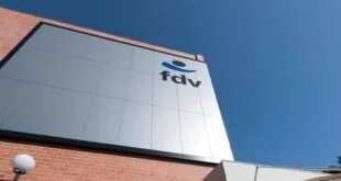 Fachada de prédio branco com o logotipo 'fdv' recortado contra o céu azul