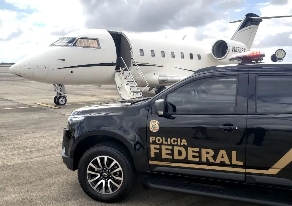 Viatura da Polícia Federal estacionada ao lado de um jato executivo em pista de aeroporto