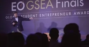 Pessoa em palco diante de telão com os dizeres 'GSEA Final' e 'Student Entrepreneur'