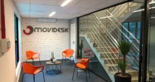 Recepção de escritório com poltronas laranja e letreiro Movidesk na parede