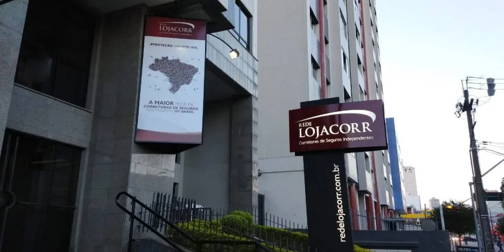 Banners da Rede Lojacorr na entrada de um edifício em dia nublado
