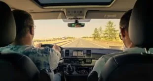 Vista do interior de um carro com motorista e passageiro em estrada de pista simples