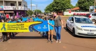 Pessoas caminham por rua carregando uma grande faixa azul em manifestação sobre trânsito