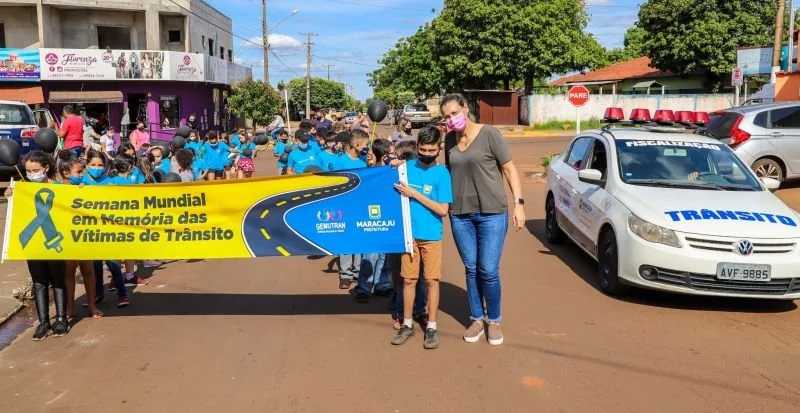 Pessoas caminham por rua carregando uma grande faixa azul em manifestação sobre trânsito