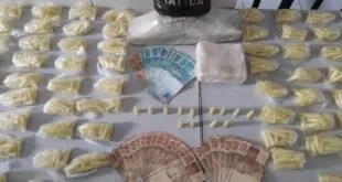 Dezenas de embalagens de droga, cédulas de real e colete com a inscrição 'Força Tática' sobre mesa