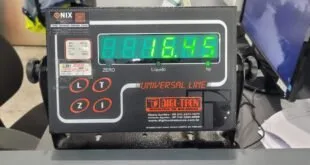 Visor de balança digital marcando 16,45 quilos sobre uma mesa de escritório