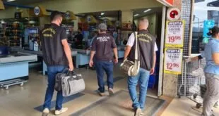 Fiscais de colete escuro entrando em estabelecimento comercial carregando bolsas