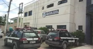 Viaturas estacionadas em frente a prédio com letreiro da Polícia Civil