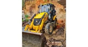 Retroescavadeira amarela trabalhando em encosta de terra após deslizamento