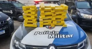 Tabletes de droga empilhados sobre o capô de viatura com a inscrição 'Polícia Militar'