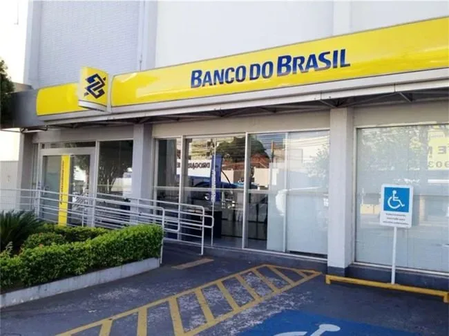 Fachada de agência do Banco do Brasil com letreiro amarelo e azul sobre a entrada