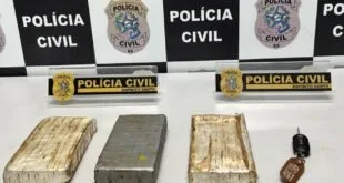 Tabletes de maconha prensada sobre mesa diante de coletes com a inscrição 'Polícia Civil'