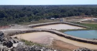 Vista aérea de área de mineração com lagoas de água barrenta cercadas por mata