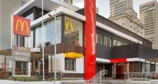 Fachada de loja do McDonald's com totem vermelho e arcos dourados na entrada