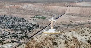 Vista aérea de grande estátua branca de Cristo sobre morro árido ao lado de estrada