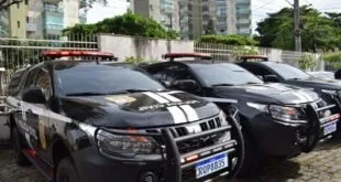 Viaturas pretas da Polícia Civil estacionadas em fila diante de prédio residencial