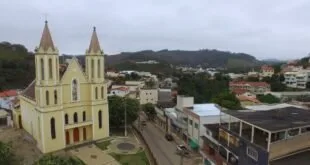 Vista do alto de cidade com igreja de torre pontiaguda e casas ao longo da rua