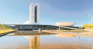 Prédio do Congresso Nacional refletido no espelho d'água sob céu azul