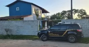 Viatura da Polícia Federal parada em frente a um sobrado durante operação