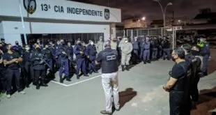 Policiais militares em formação noturna diante de painel com a inscrição '13ª Cia Independente'