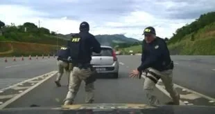 Agentes da PRF correm em direção a carro branco parado na pista durante abordagem