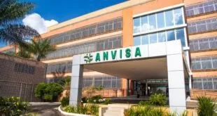 Fachada de prédio moderno com o letreiro 'Anvisa' e jardim à frente