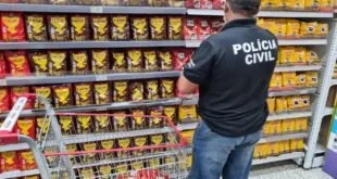 Agente com colete da Polícia Civil observa prateleira cheia de pacotes de café em supermercado