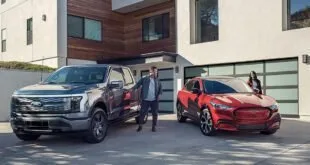 Caminhonete e SUV vermelho estacionados na entrada de uma casa moderna, com pessoas ao lado