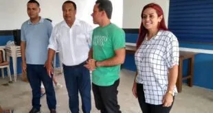 Grupo de cinco pessoas conversa em pé dentro de salão claro durante encontro