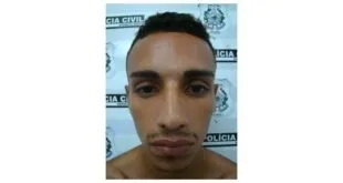Homem fotografado de frente diante de parede com o brasão e o nome Polícia Civil