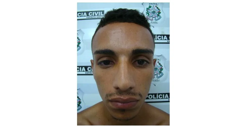 Homem fotografado de frente diante de parede com o brasão e o nome Polícia Civil