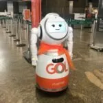 Robô branco e laranja com a marca Gol parado no saguão de um aeroporto