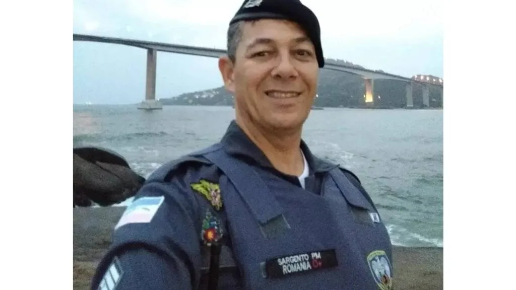 Policial militar fardado em selfie com ponte sobre o mar ao fundo