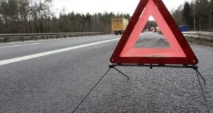 Triângulo de sinalização vermelho posicionado sobre o asfalto de uma rodovia