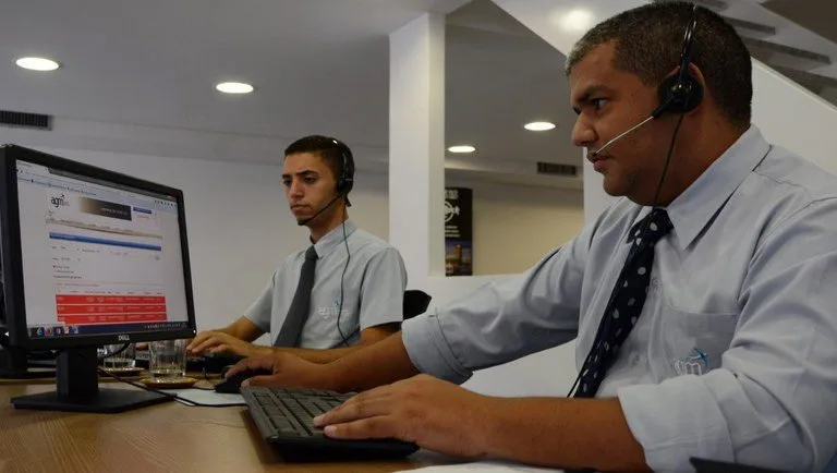 Dois homens de camisa e gravata trabalham em computadores, imagem ilustrativa sobre emprego
