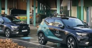 Carro elétrico estacionado sobre placa de recarga sem fio em via urbana