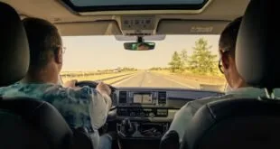 Motorista e passageira dentro de carro em viagem por rodovia, vistos do banco de trás