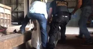 Agentes da Polícia Federal carregam sacos brancos até forno em galpão industrial