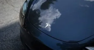 Emblema da Tesla em relevo sobre carroceria preta e brilhante de carro