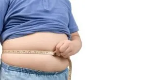 Homem de camisa azul segura dobra de gordura na barriga, imagem ilustrativa sobre obesidade